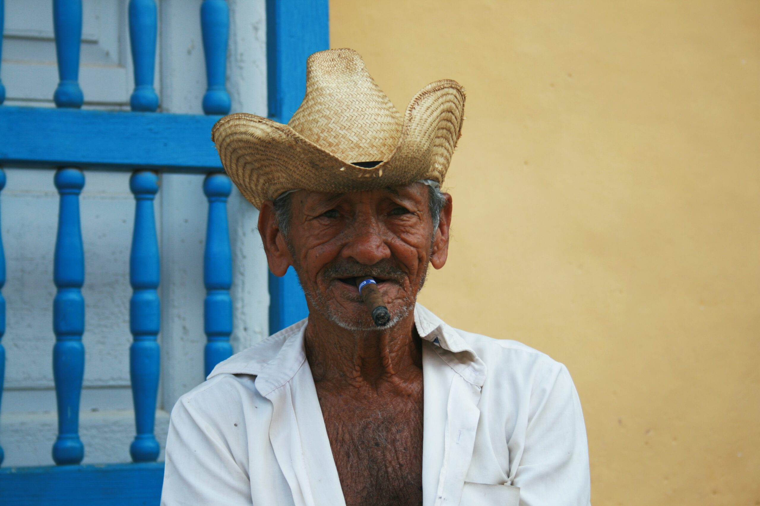 Kubaner mit Hut und Zigarre vor einem Haus sitzend